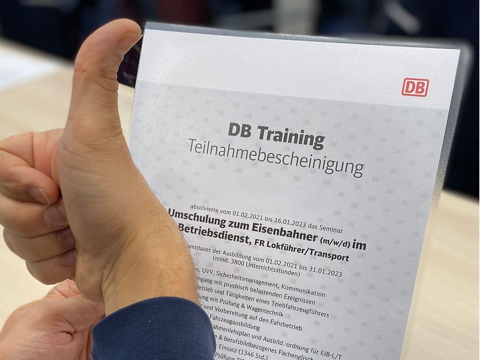 Zu sehen ist eine Urkunde und eine Hand die den Daumen nach oben zeigt.