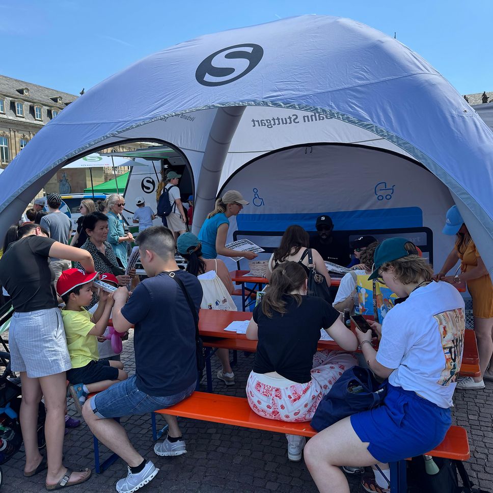 Am Basteltisch der S-Bahn Stuttgart ist viel los. Kinder und Familien sitzen zusammen und basteln.